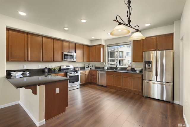 kitchen with brown cabinets, dark wood finished floors, a peninsula, and stainless steel appliances