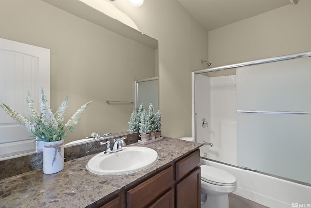 bathroom with enclosed tub / shower combo, vanity, and toilet