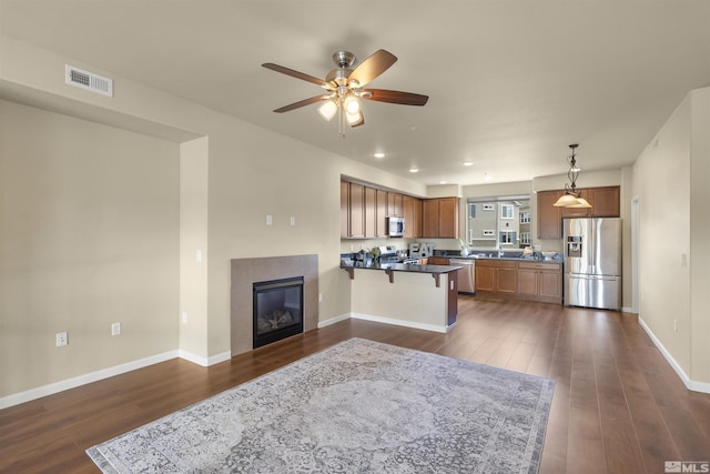 kitchen with appliances with stainless steel finishes, dark countertops, dark wood finished floors, and visible vents