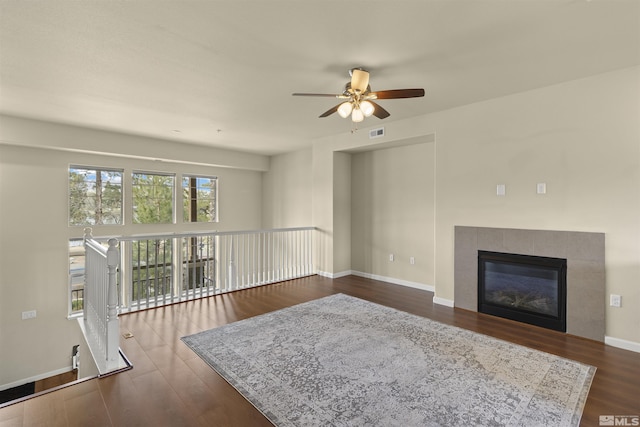 living room with visible vents, baseboards, ceiling fan, a fireplace, and dark wood-style floors