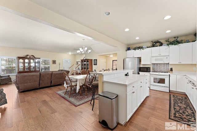 kitchen featuring open floor plan, light wood-type flooring, white appliances, and a chandelier