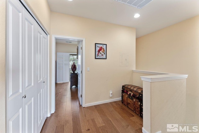 corridor with visible vents, baseboards, an upstairs landing, recessed lighting, and wood finished floors