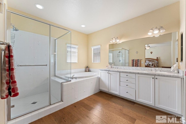 full bathroom with a sink, a shower stall, wood finished floors, and a garden tub