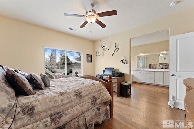 bedroom with light wood finished floors, visible vents, connected bathroom, and ceiling fan