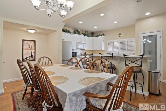 dining space with light wood-style flooring, baseboards, recessed lighting, and a notable chandelier