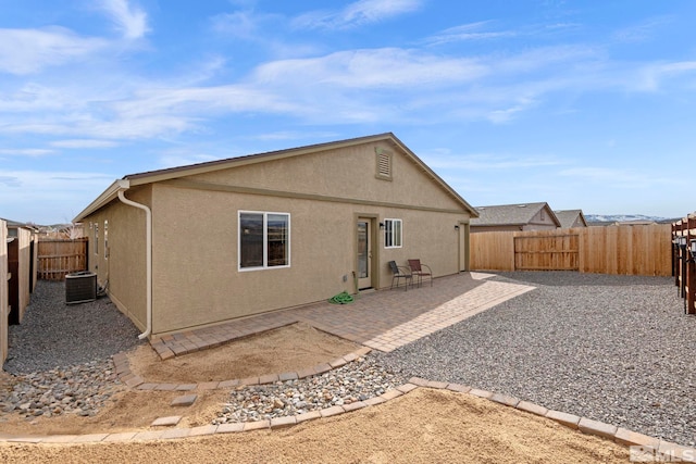 rear view of property with a patio, central AC, a fenced backyard, and stucco siding