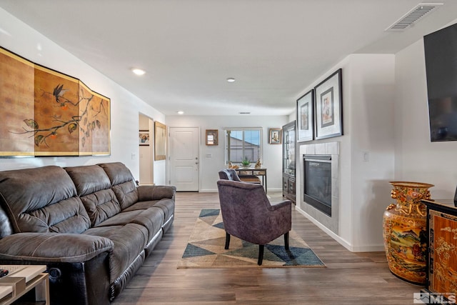 living room with visible vents, baseboards, a fireplace, recessed lighting, and wood finished floors