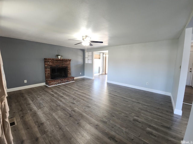 unfurnished living room featuring ceiling fan, a fireplace, visible vents, baseboards, and dark wood-style floors