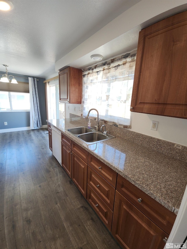 kitchen with an inviting chandelier, light stone counters, a sink, white dishwasher, and dark wood-style floors