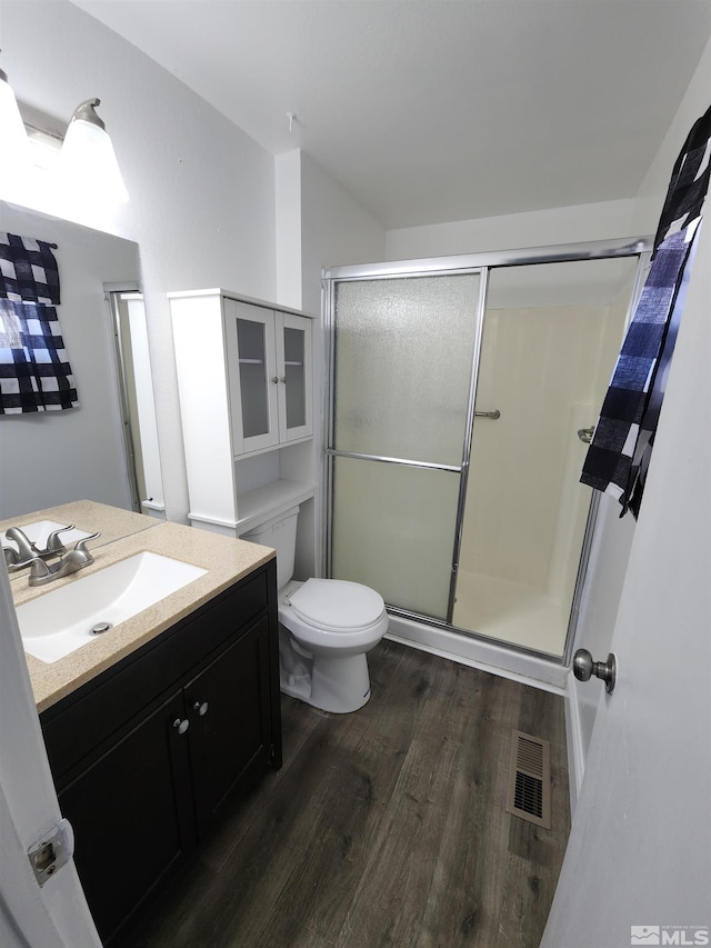bathroom featuring a shower stall, wood finished floors, vanity, and visible vents