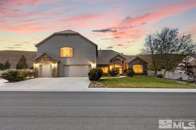 view of front of property with a front yard, fence, stone siding, an attached garage, and driveway