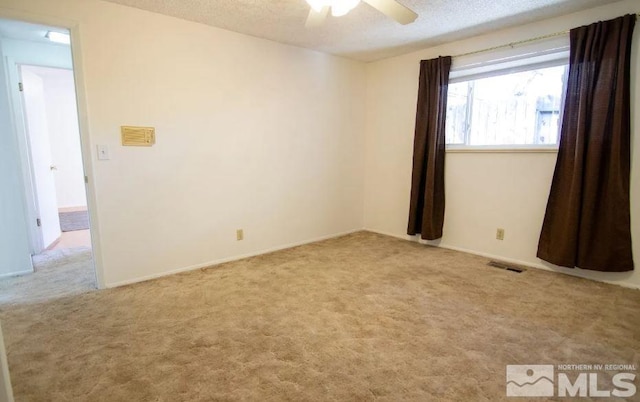 spare room featuring a textured ceiling, visible vents, a ceiling fan, and carpet