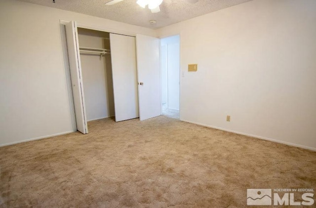 unfurnished bedroom featuring a textured ceiling, a closet, carpet flooring, and ceiling fan