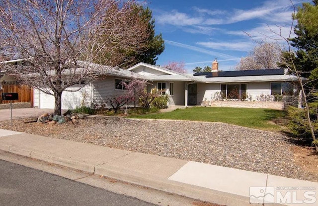 ranch-style house with roof mounted solar panels, a chimney, fence, concrete driveway, and a front lawn