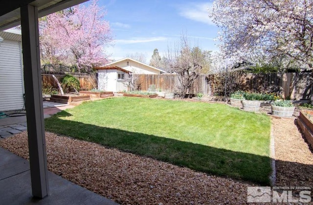view of yard featuring a garden, a fenced backyard, and an outdoor structure