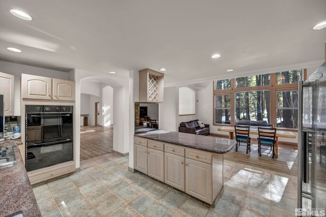 kitchen with arched walkways, dobule oven black, and recessed lighting