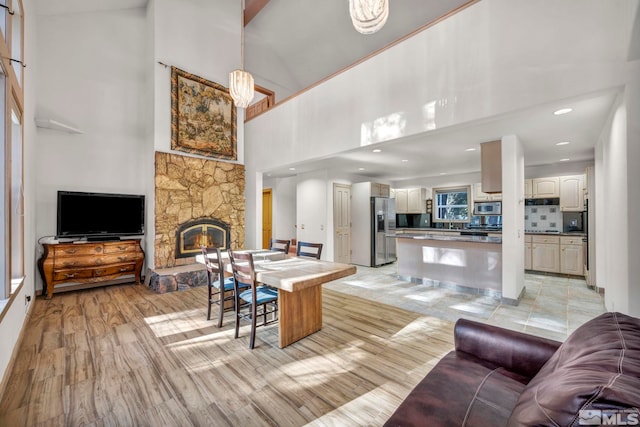 living room featuring recessed lighting, a stone fireplace, and a high ceiling