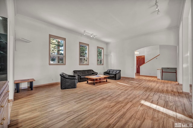sitting room with crown molding, light wood-style floors, rail lighting, arched walkways, and baseboards