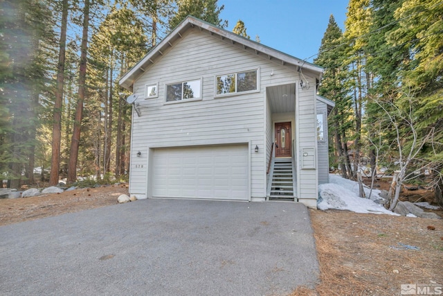 chalet / cabin featuring aphalt driveway and an attached garage