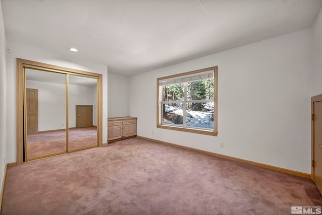 unfurnished bedroom with a closet, recessed lighting, light colored carpet, and baseboards