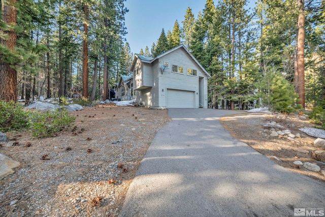 view of side of home with metal roof, a garage, and aphalt driveway