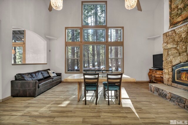 dining room with arched walkways, a towering ceiling, a ceiling fan, wood finished floors, and baseboards