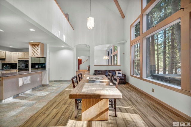 dining space featuring high vaulted ceiling, arched walkways, recessed lighting, baseboards, and beam ceiling