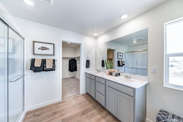 bathroom with a stall shower, wood finished floors, a sink, and a spacious closet