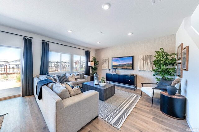 living room featuring recessed lighting, an accent wall, wallpapered walls, and wood finished floors