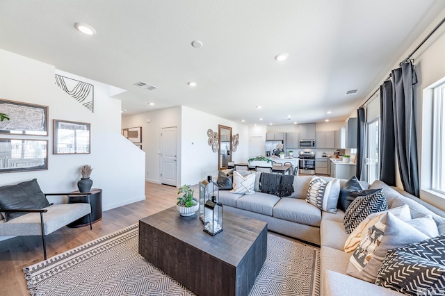 living area with light wood-style floors, baseboards, visible vents, and recessed lighting