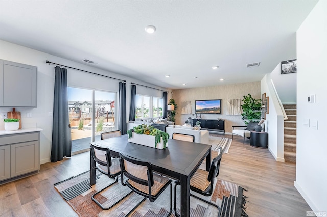dining space with visible vents, baseboards, light wood-style floors, and stairs