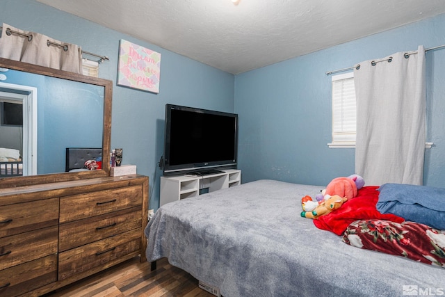 bedroom with a textured ceiling and wood finished floors