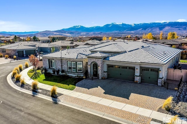 single story home featuring stone siding, a mountain view, decorative driveway, and a garage