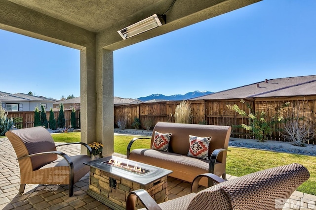 view of patio featuring a fenced backyard, a mountain view, and an outdoor living space with a fire pit