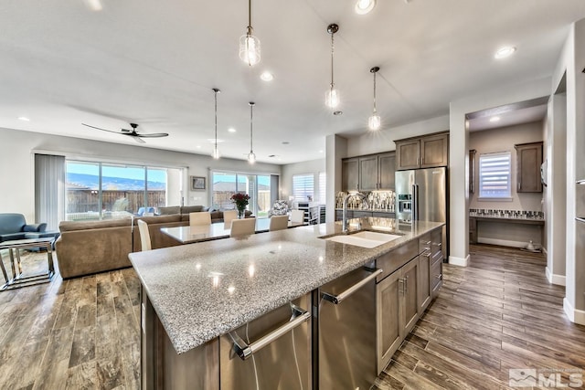 kitchen featuring a sink, open floor plan, dark wood-type flooring, and a center island with sink