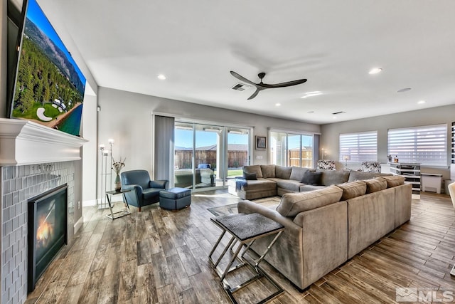 living room with a tiled fireplace, ceiling fan, wood-type flooring, and recessed lighting