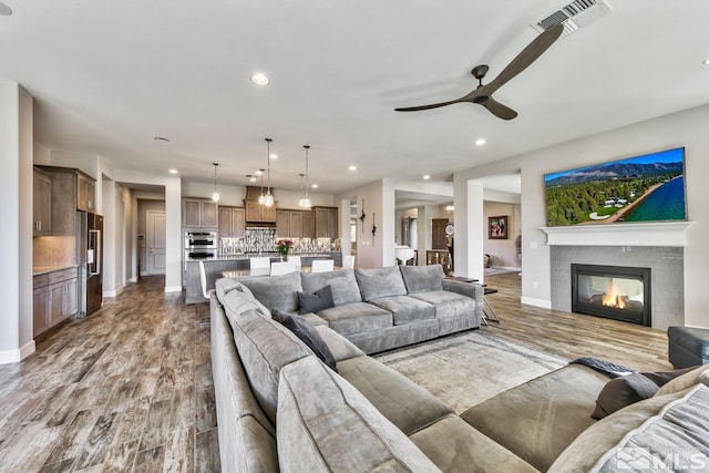 living room with visible vents, recessed lighting, and wood finished floors