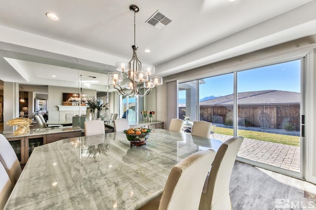 dining room with an inviting chandelier, visible vents, recessed lighting, wood finished floors, and a raised ceiling