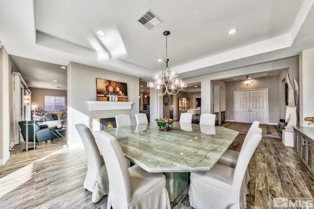dining area with recessed lighting, dark wood-type flooring, visible vents, a brick fireplace, and a raised ceiling