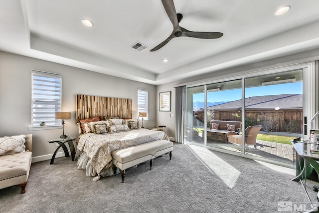 carpeted bedroom with visible vents, baseboards, a tray ceiling, recessed lighting, and access to outside