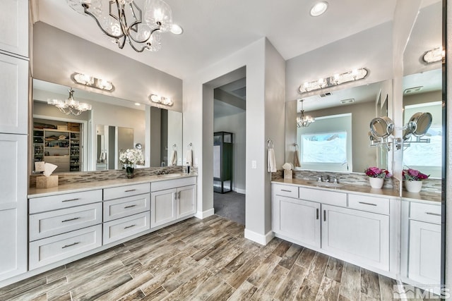full bathroom with wood finished floors, an inviting chandelier, and vanity