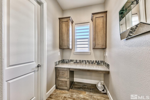 bathroom featuring wood finished floors, a textured wall, and baseboards