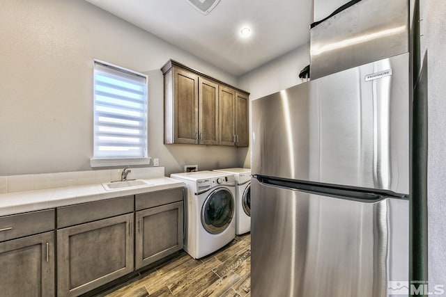 washroom featuring a sink, washing machine and dryer, and dark wood-type flooring