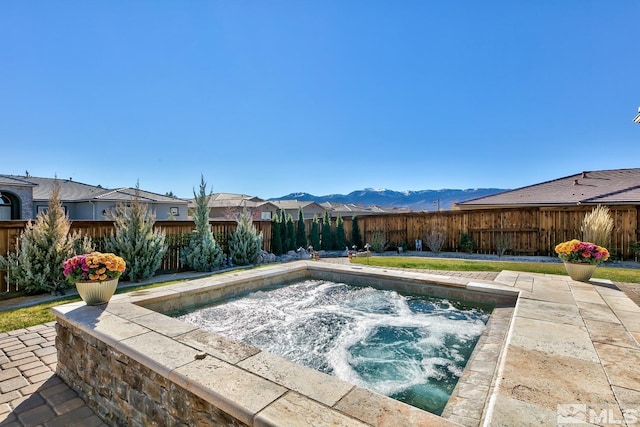 view of swimming pool featuring an in ground hot tub, a mountain view, and fence