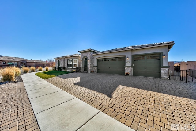 prairie-style house featuring stone siding, decorative driveway, a gate, and a garage