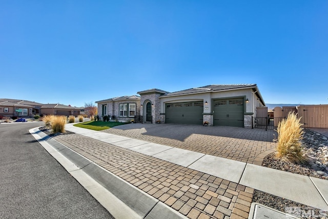 view of front of house featuring decorative driveway, fence, stone siding, a gate, and an attached garage