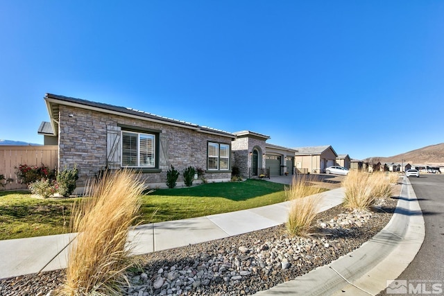 view of front facade featuring a front yard, stone siding, a garage, fence, and driveway