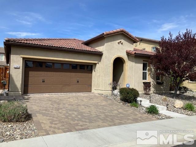mediterranean / spanish-style home featuring an attached garage, a tiled roof, stucco siding, and decorative driveway