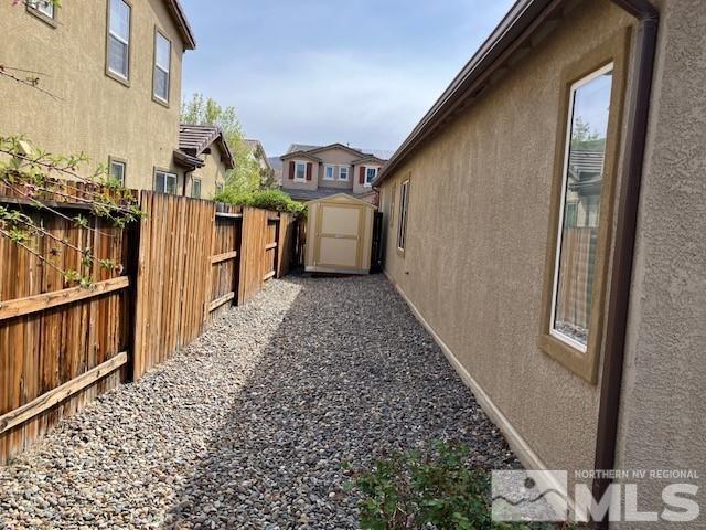 view of home's exterior with stucco siding, a storage shed, fence, and an outbuilding