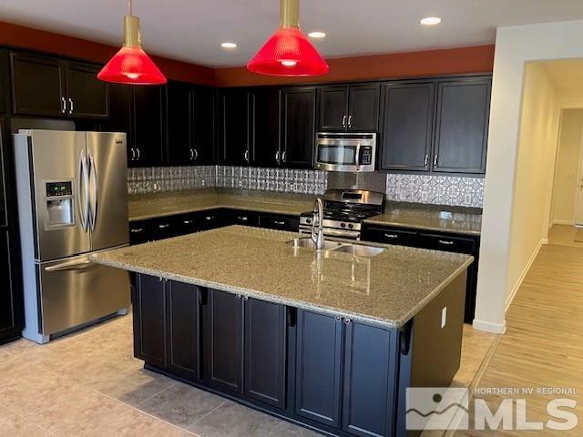 kitchen featuring a sink, backsplash, light stone countertops, and stainless steel appliances